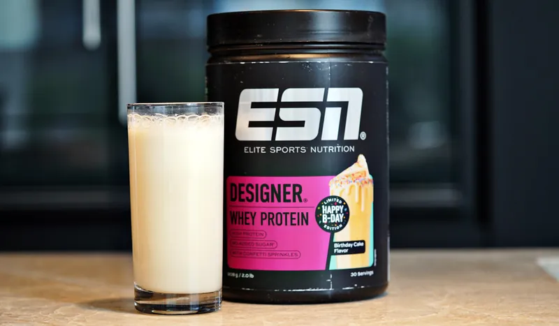 ESN Designer Whey Protein – Birthday Cake, con un bicchiere