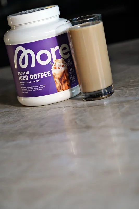 More Protein Iced Coffee – White Almond Coconut, con un bicchiere